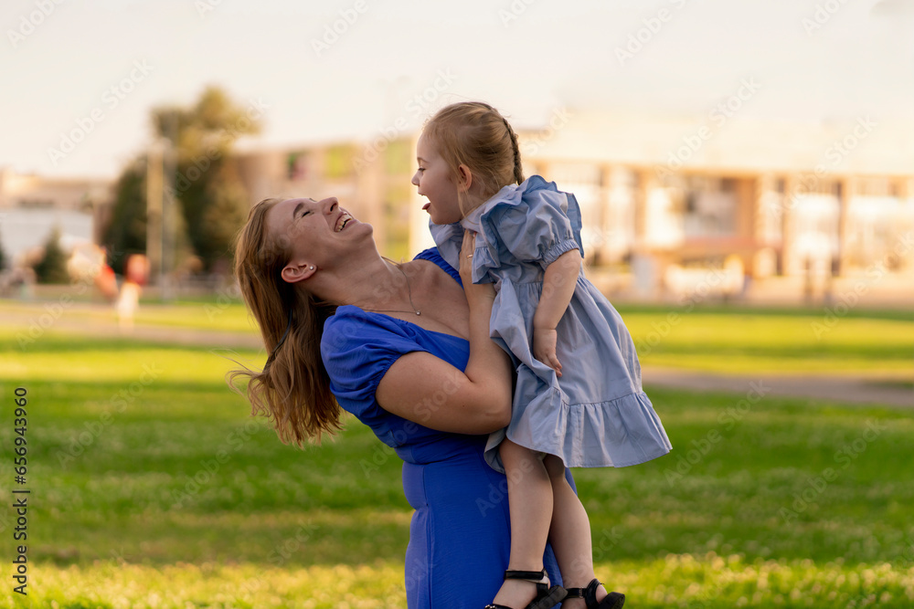 Fototapeta premium a young happy smiling female holding her little daughter on her hands
