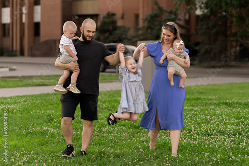 parents mom and dad walk in the park with their kids and hold dayghter in hands