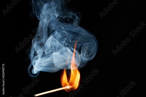 zündendes Streichholz mit Flamme und Rauch vor schwarzem Hintergrund