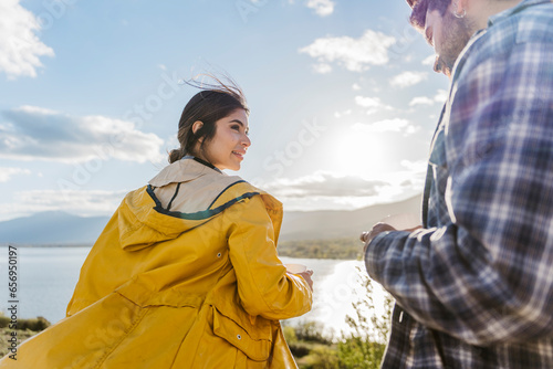 Woman wearing jacket looking at man having coffee