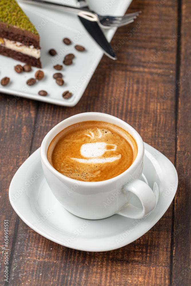 Patterned cappuccino coffee in a white porcelain cup on a wooden table Patterned cappuccino coffee in a white porcelain cup on a wooden table