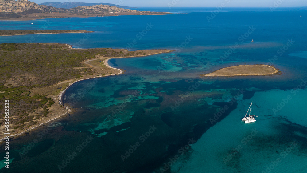 Aerial photo of the island of Isola Piana near Stintino and the beach of Spiaggia La Pelosa. Mountainous island, blue water and clear sky. Northwest part of Sardinia, Sassari Province, Italy.