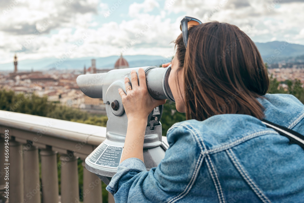 Woman looking through binoculars standing at balustrade Woman looking through binoculars standing at balustrade