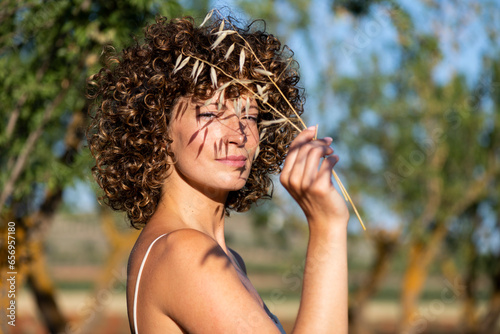 Woman with curly hair holding twig photo