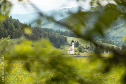 Church of St. Magdalena in front of mountains and pine forest photo