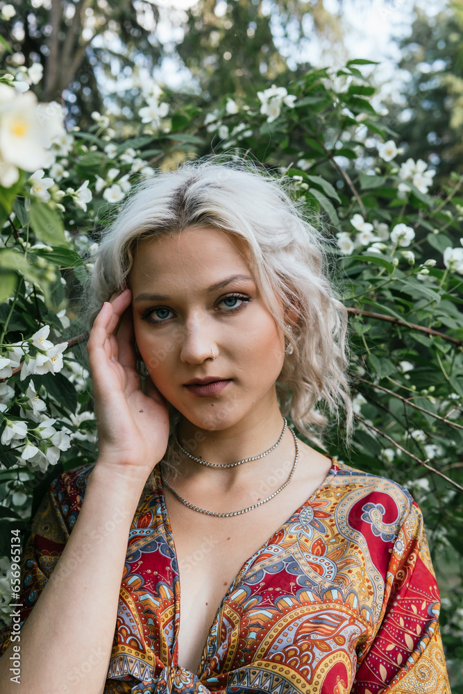 Beautiful woman touching face and standing in front of flower plant Beautiful woman touching face and standing in front of flower plant