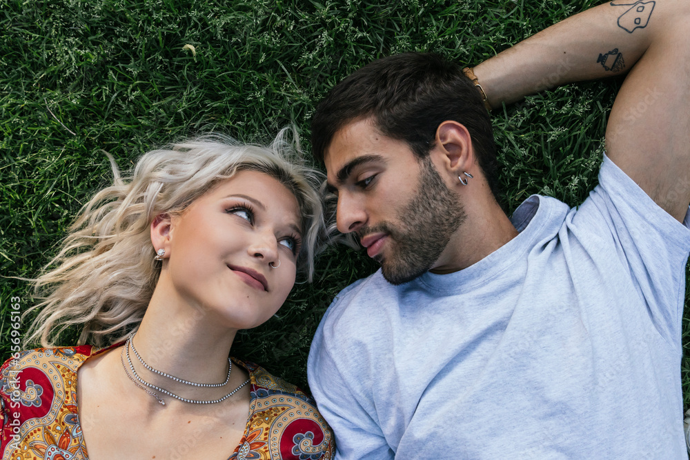 Young couple staring at each other lying on grass Young couple staring at each other lying on grass