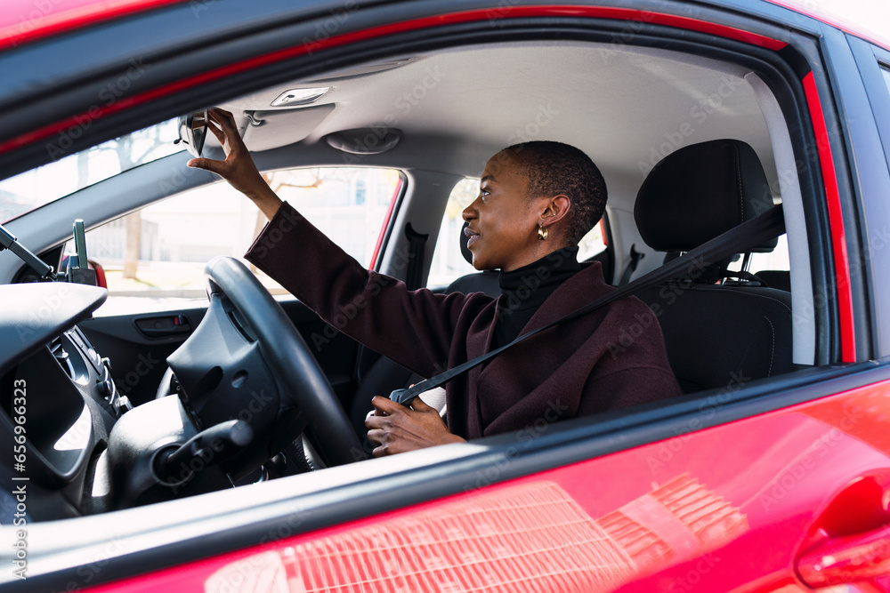 Woman adjusting rear-view mirror in car Woman adjusting rear-view mirror in car