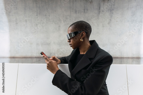 Young woman wearing smart glasses using smart phone at metro station photo