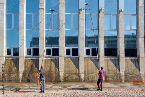 Professional cleaning service workers washes windows with special equipment. Telescopic equipment for washing glass.