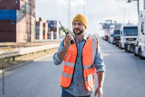 Truck driver wearing knit hat talking on walkie-talkie