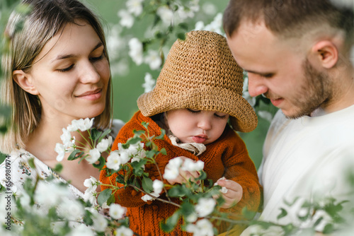 Smiling parents with child spending leisure time in garden
