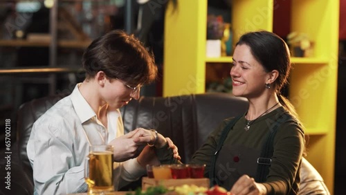 A young, handsome guy confesses his love to the girl while sitting at a table in the bar photo