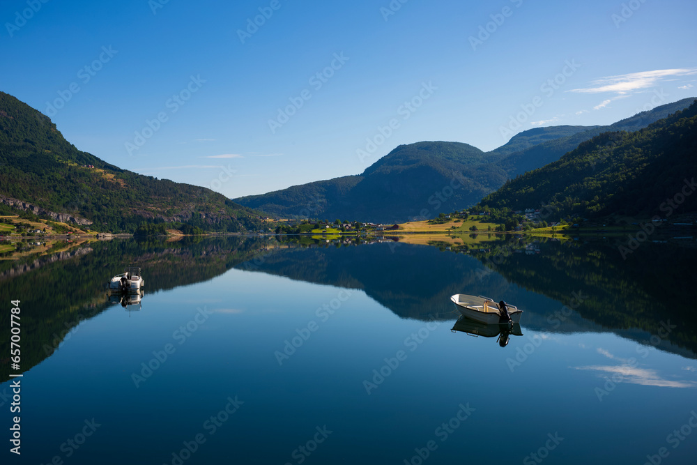 Reflections of two boats in a Norway fjord during a summer morning