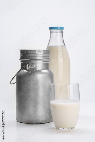 fresh milk in glass bottle with aluminum can and glass cup on white background