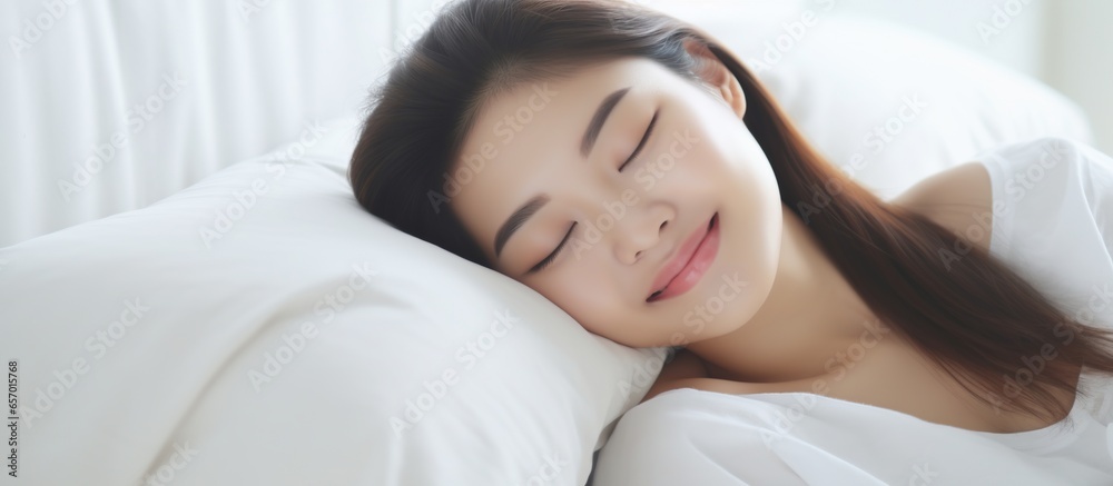 Portrait of beautiful Asian woman with attractive smile enjoying fresh soft mattress in white bedroom