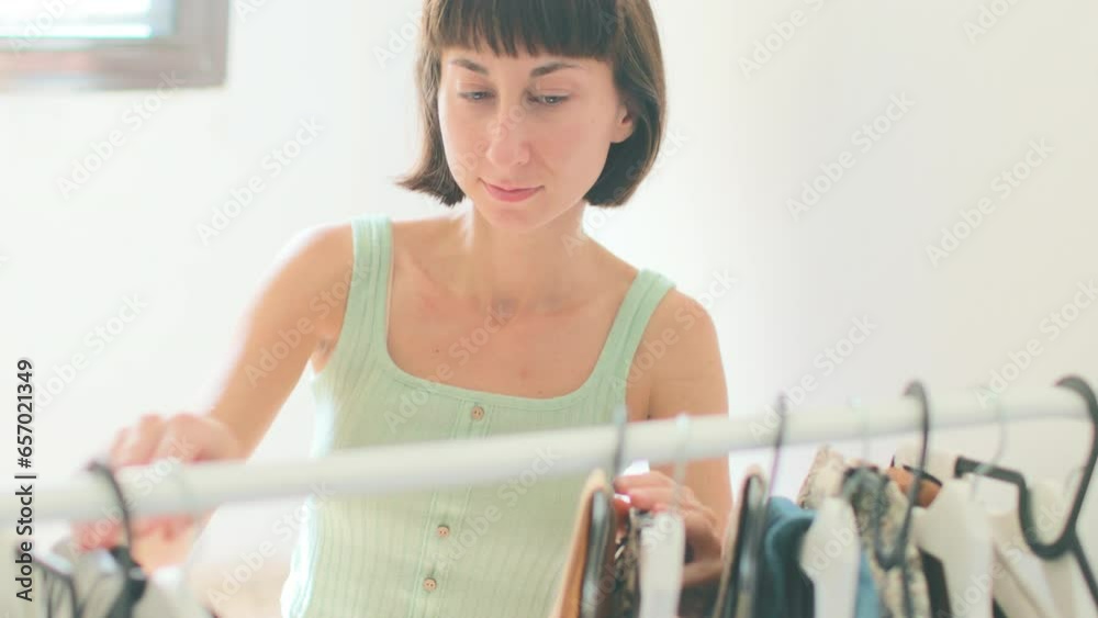 Beautiful attractive girl choosing clothes on a clothes rack, Girl thinking about what to wear. Lifestyle of women relaxing at home.