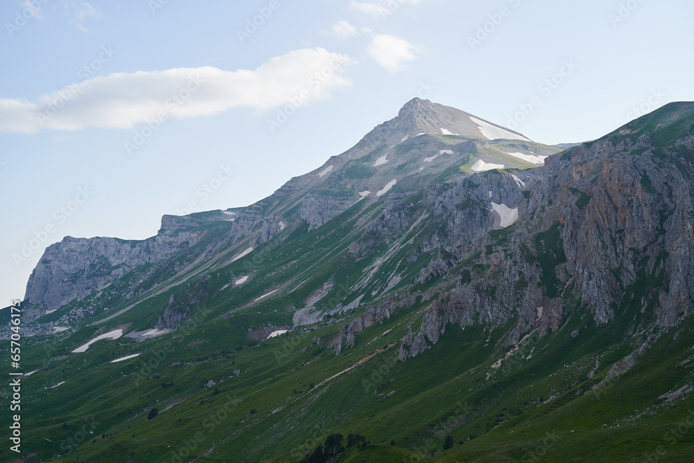 Landscape with a mountain range surrounded by green alpine meadows.