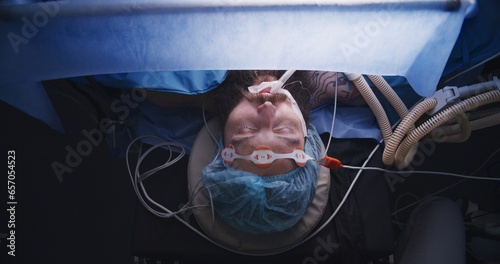 Quadro em tela Close up top view of male patient sleeps under anesthesia on surgical table during difficult surgery in hospital