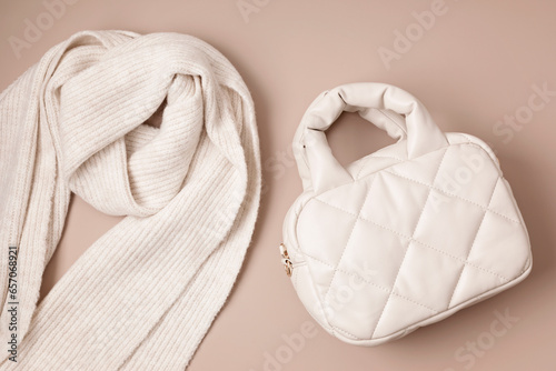 Beige quilted puffed bag and woolen scarf on pastel background. Stylish woman outerwear. Winter fashion accessories