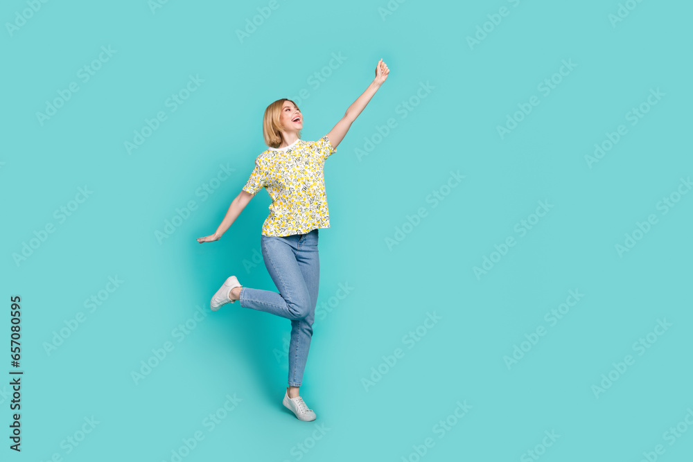 Full length photo of impressed funky lady wear flower print t-shirt holding arm empty space isolated turquoise color background Full length photo of impressed funky lady wear flower print t-shirt holding arm empty space isolated turquoise color background