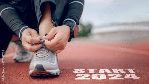 Athletes are getting ready to run on the track with text Start 2024 in New Year's start concept.