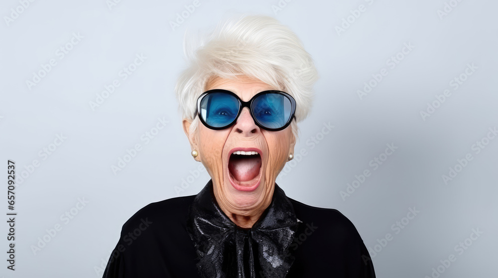 Funny stylish elderly grandmother in glasses poses at studio. Senior old woman looking at camera over bright background. Funny stylish elderly grandmother in glasses poses at studio. Senior old woman looking at camera over bright background.