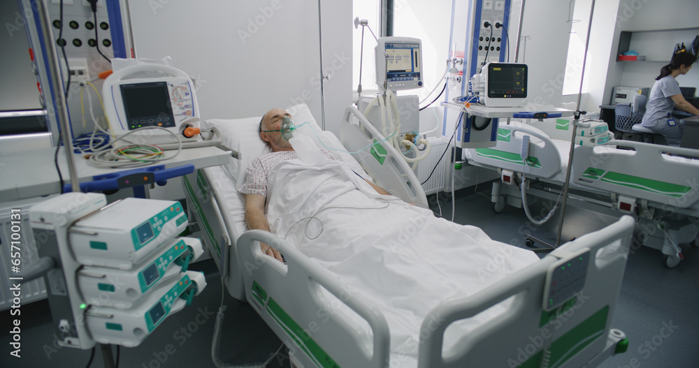 Sick elderly man in oxygen mask sleeps in bed in hospital ward. Old
