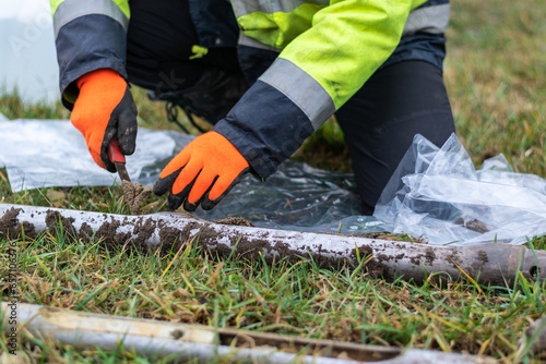 Worker collects soil samples from core drill and putting them to plastic bags, closeup side view