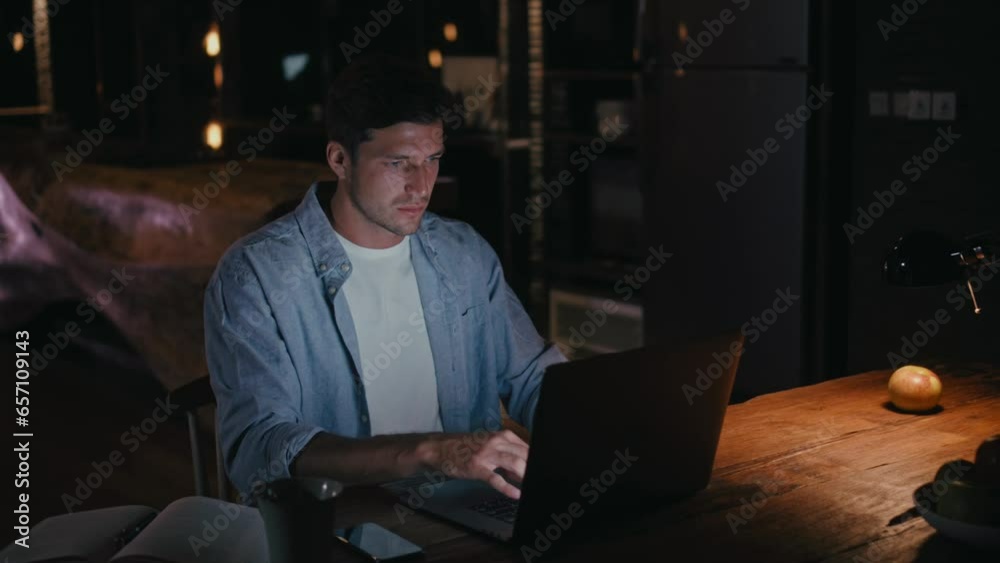 Man working late night on laptop in dimly lit room Man working late night on laptop in dimly lit room