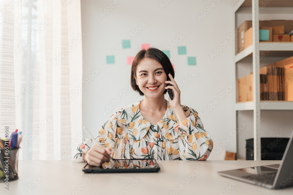 Portrait entrepreneur Asian woman working on laptop at office while talking on phone at home office. Businesswoman online working. Small business concept. Portrait entrepreneur Asian woman working on laptop at office while talking on phone at home office. Businesswoman online working. Small business concept.
