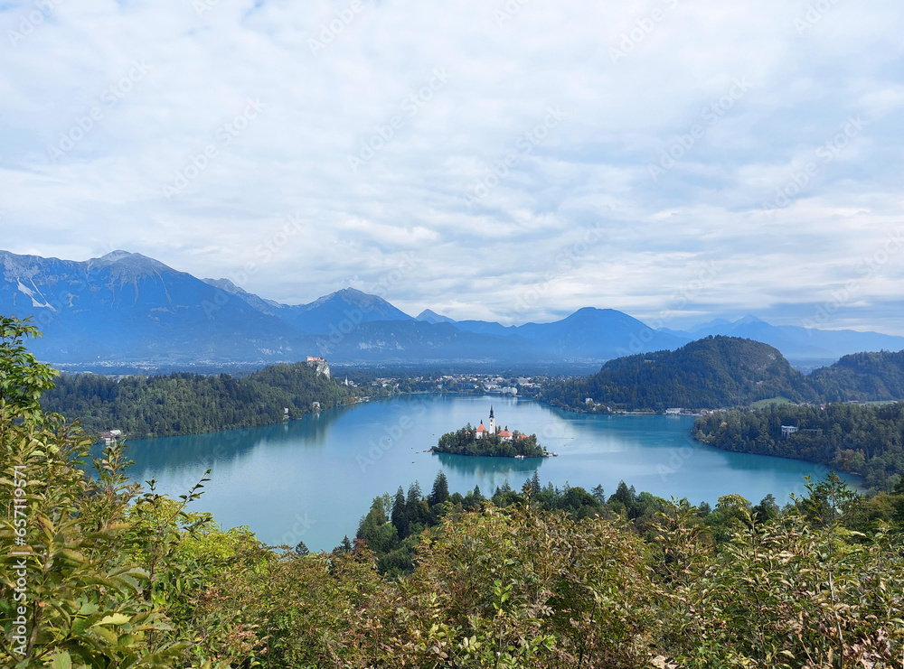 view to the island on lake Bled and dark blue mountains. Slovenia under white clouds