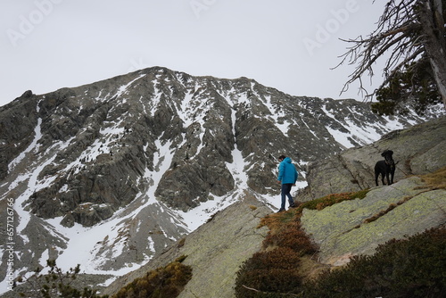 Man and dog hiking snowy mountain 