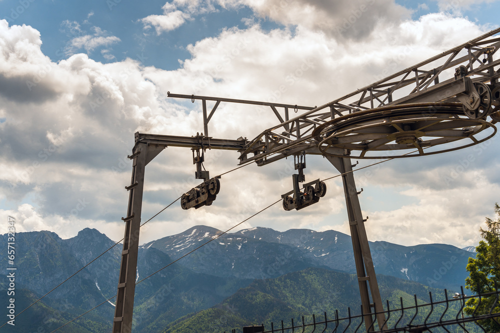 Mountain cable car lift on a stunning backdrop of the Tatra Mountains in Zakopane, Poland, under a cloudy blue sky. The embodiment of the concept of mountain adventure and scenic beauty