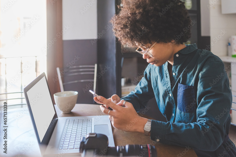 Young multiethnic woman indoors at home using computer and smartphone ...