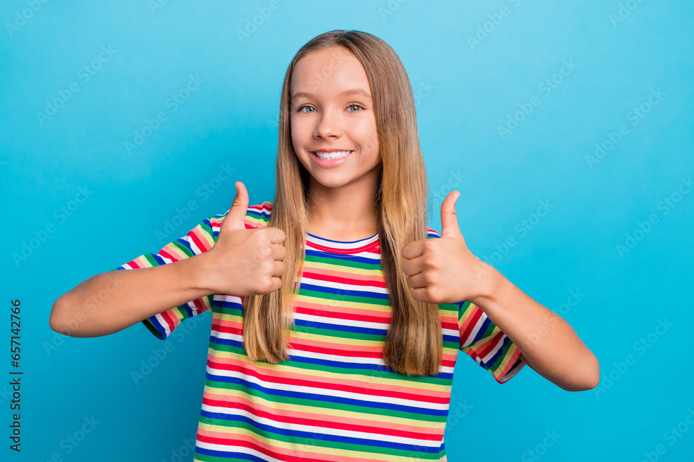 Portrait of satisfied teen girl with long hair wear colorful t-shirt two arms showing thumbs up approve isolated on blue color background Portrait of satisfied teen girl with long hair wear colorful t-shirt two arms showing thumbs up approve isolated on blue color background
