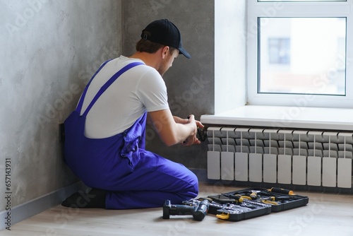 heating system installation and maintenance service. plumber installing radiator.