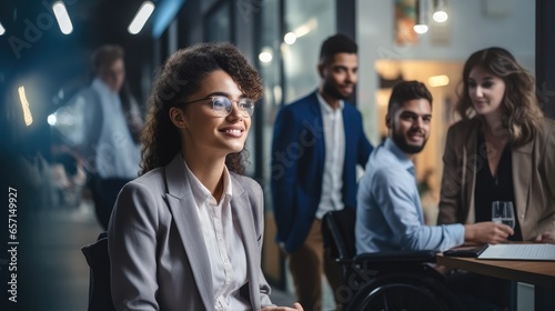 Disabled Business woman sitting in a wheelchair having a meeting with colleagues in an office space.