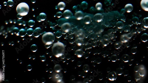 Fizzy translucent bubbles rising slowly on a black background.