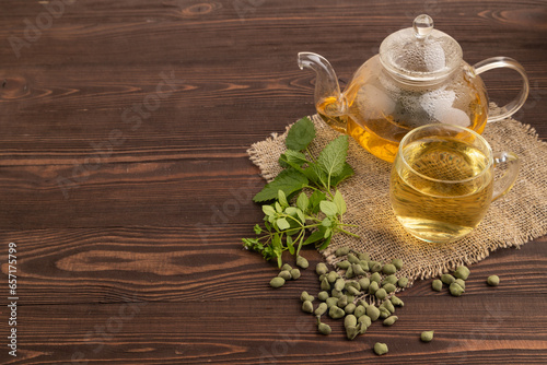 Green oolong tea with herbs in glass on brown wooden. Side view, copy space.