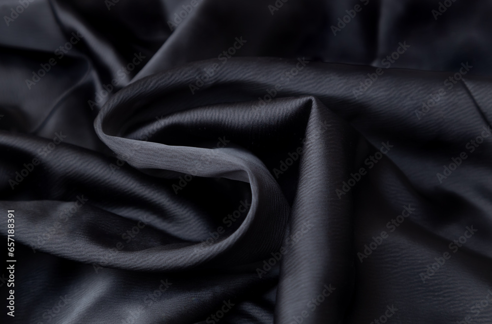 Fototapeta premium Black crumpled fabric folds background. Black History Month concept. Soft focus texture of the silk fabric, soft black