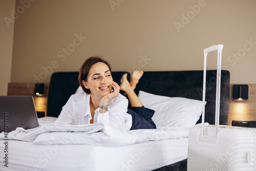 Business woman lying on bed and working on computer in a hotel room