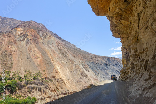 A 4x4 camper on an off-road road under a big rock photo