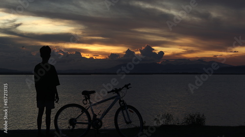 silhouette of a bicycle against the background of the sunset on the lake  © Palugada