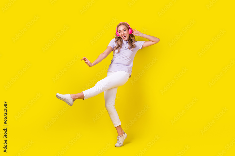 Full size photo of good mood nice girl wear violet polo white trousers having fun listen playlist isolated on yellow color background