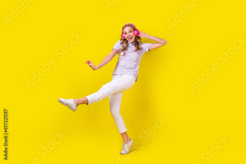 Full size photo of good mood nice girl wear violet polo white trousers having fun listen playlist isolated on yellow color background