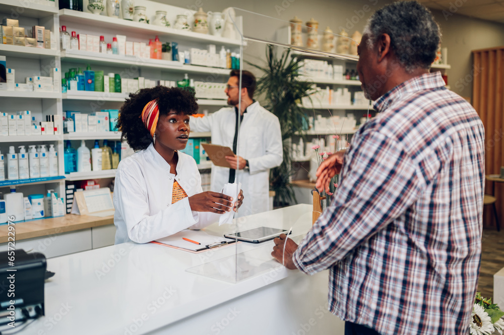 African woman pharmacist selling drugs to a senior customer in a pharmacy