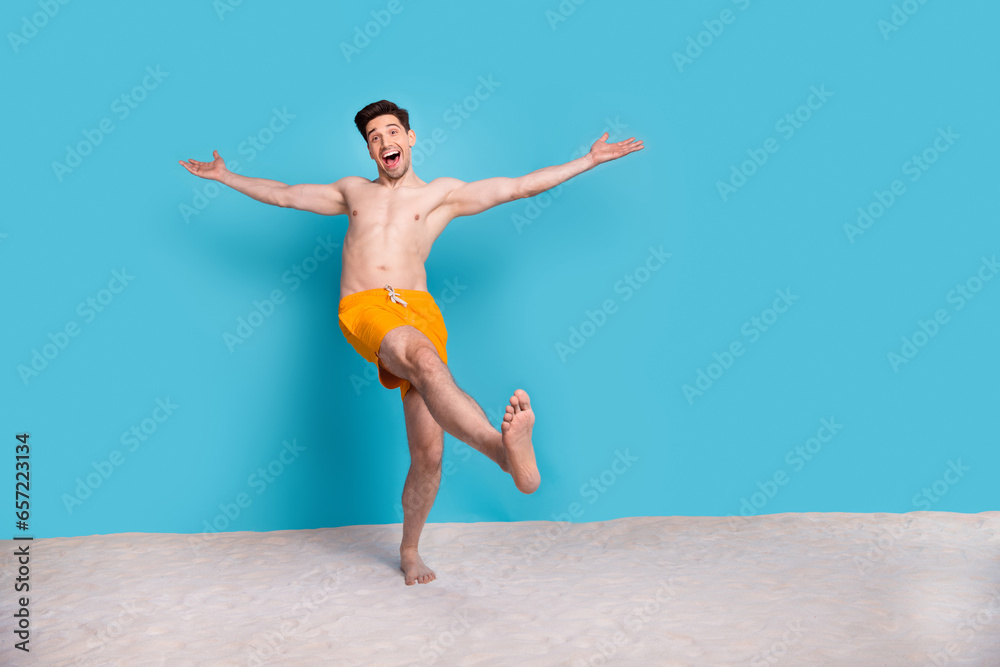 Full body photo of handsome young guy stretch hands excited dressed stylish yellow shorts isolated on blue color background summer vacation