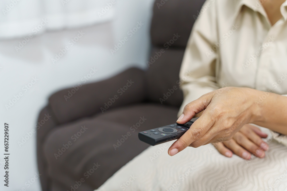 Elderly woman Watching smart TV and using remote controller Hand holding television audio remote control Middle age Asian woman movie Television series spending time at home Elderly woman Watching smart TV and using remote controller Hand holding television audio remote control Middle age Asian woman movie Television series spending time at home