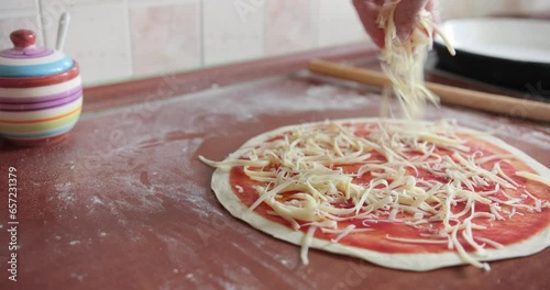 Footage of a person putting cheese over the pizza dough